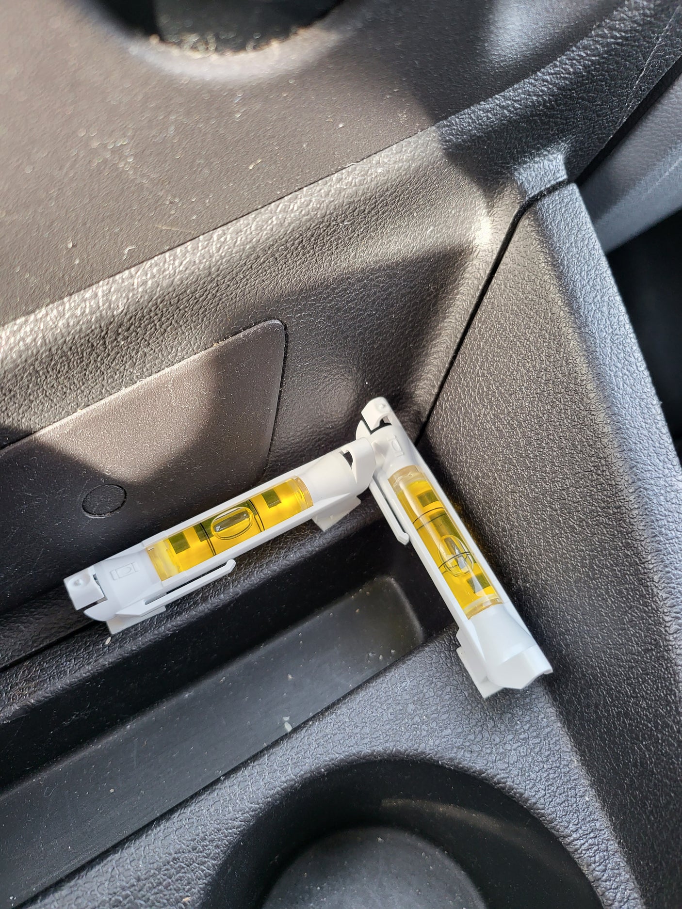 Two interconnected bubble levels rest on an RV rental's console, useful for ensuring the vehicle is level for a comfortable stay.