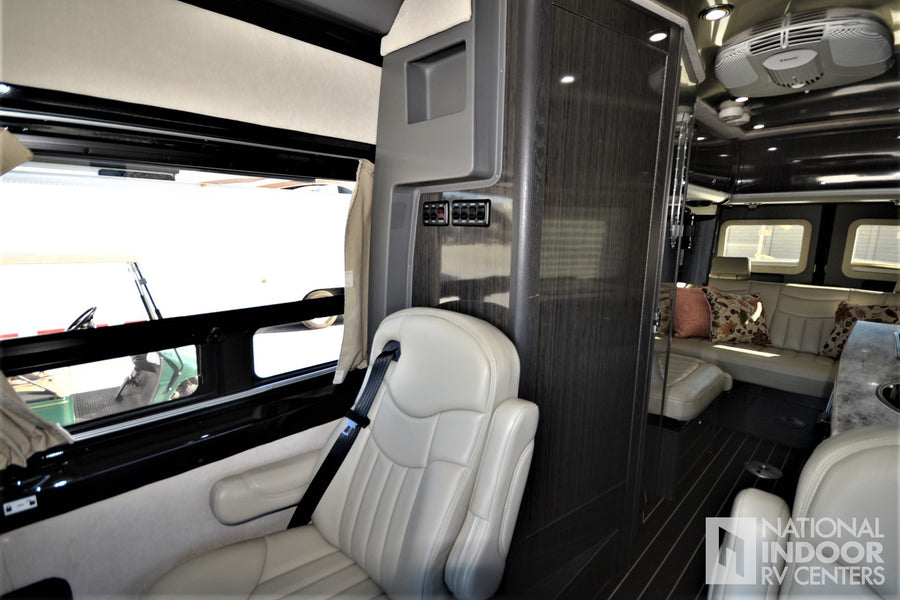 Luxury rv rental interior: cream leather seating, dark wood, Dometic AC, and large windows with outdoor view.