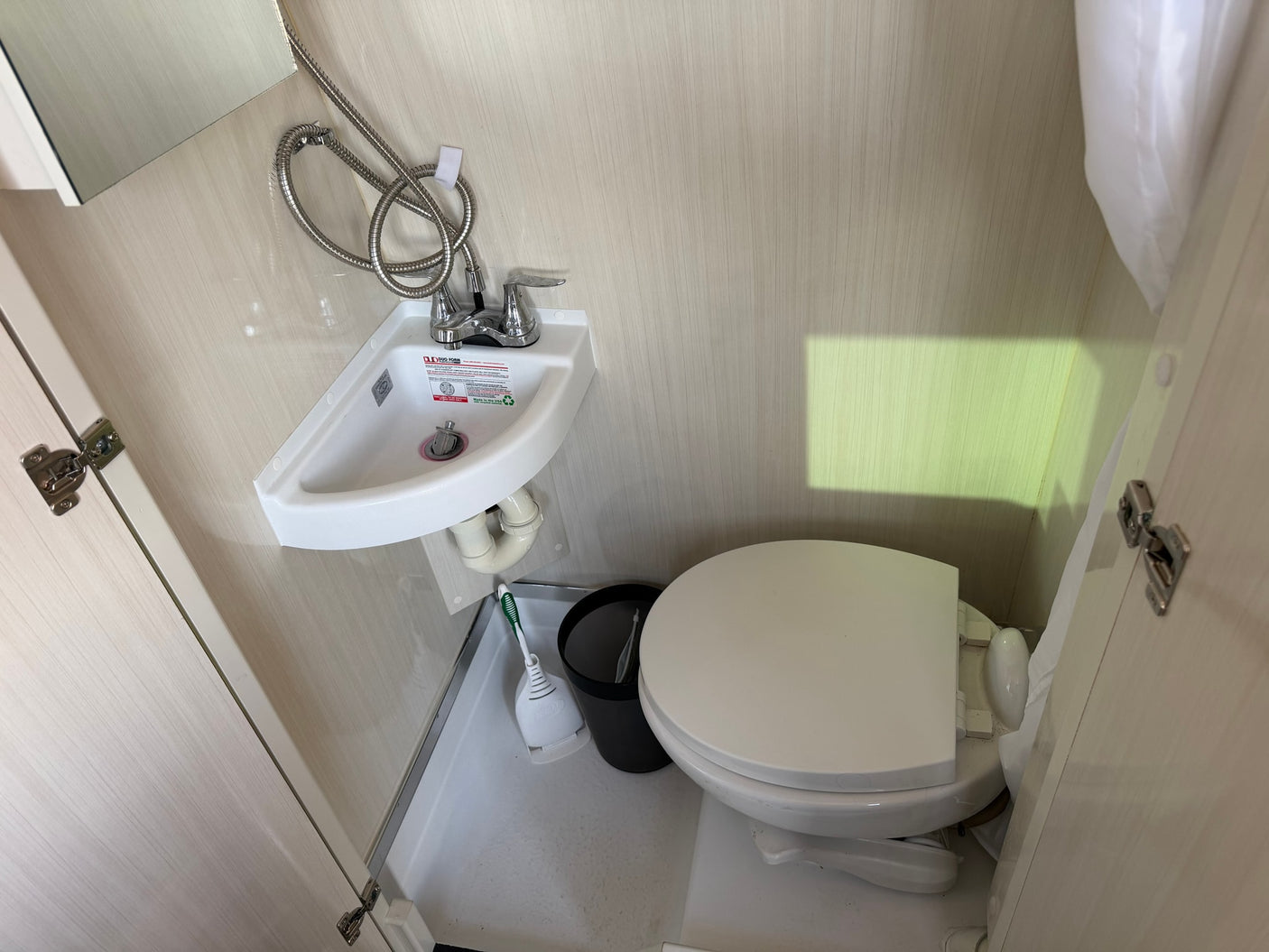 Compact RV rental bathroom with sink, toilet, and integrated shower. Ideal for small spaces.