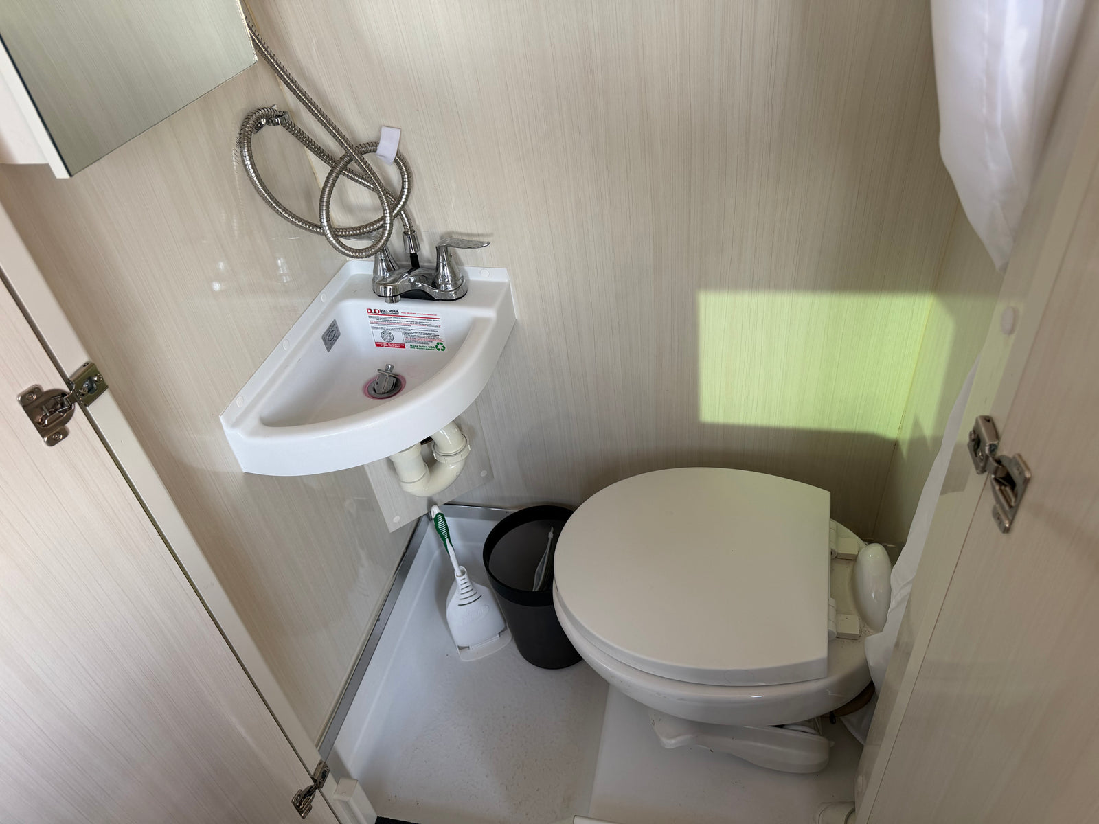 Compact RV rental bathroom with sink, toilet, and integrated shower. Ideal for small spaces.