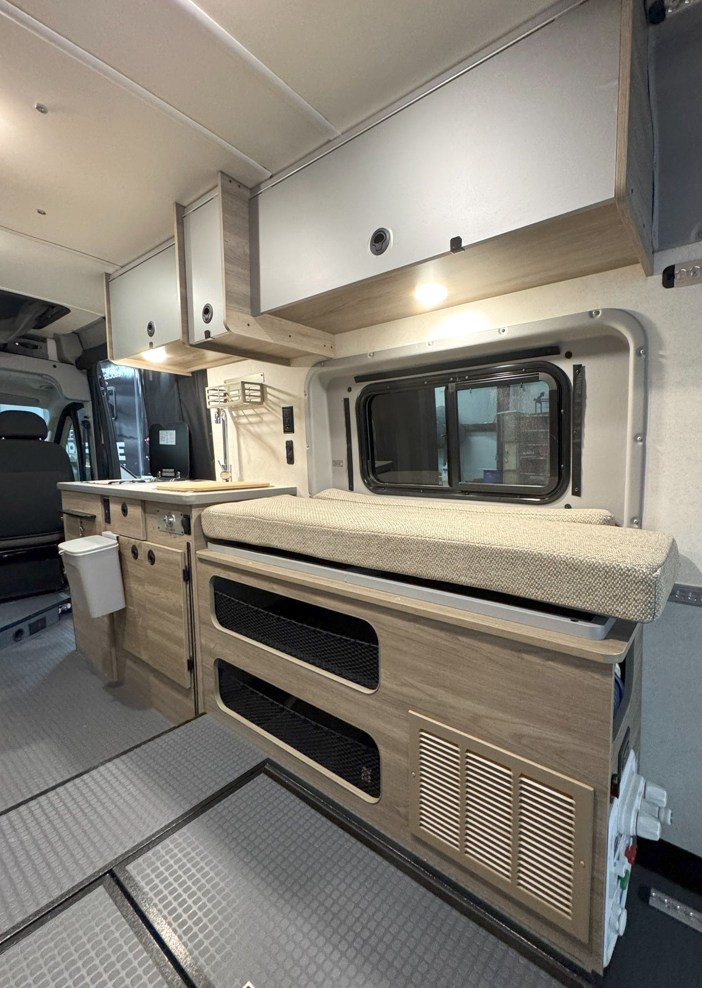 This cozy rv rental interior features a kitchenette, overhead cabinets, bench seating with integrated storage, and durable flooring.