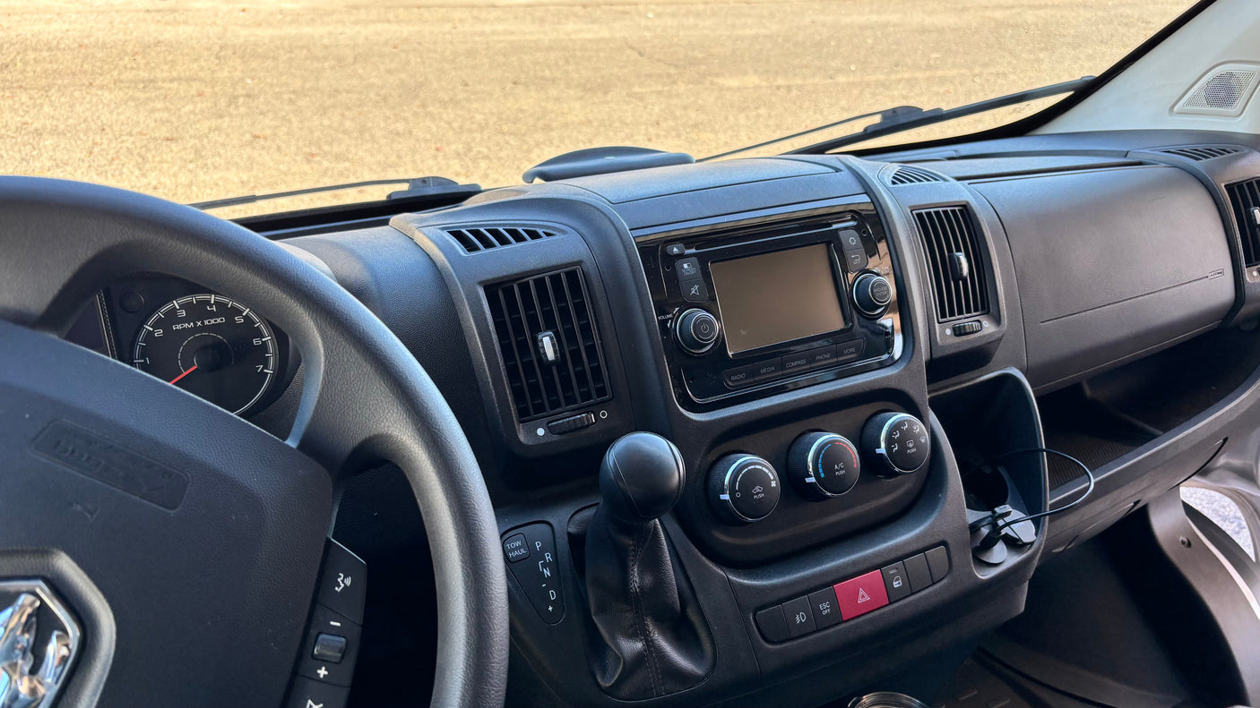 RV rental dashboard: driver's view with steering wheel, infotainment system, climate controls, and gear shifter.