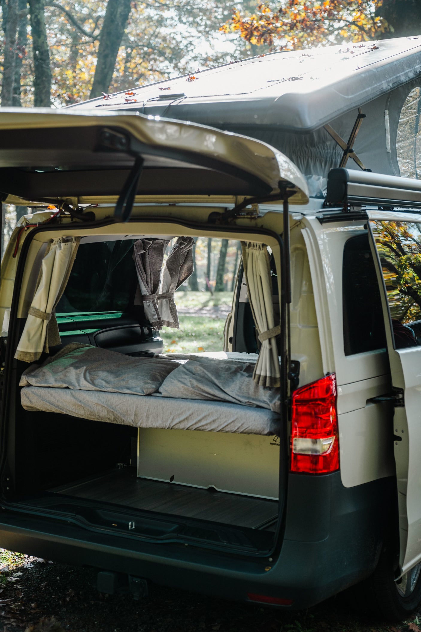 and table setup in sunlit autumn woods near a cabin.|Mercedes Metris RV rental equipment list: kitchen