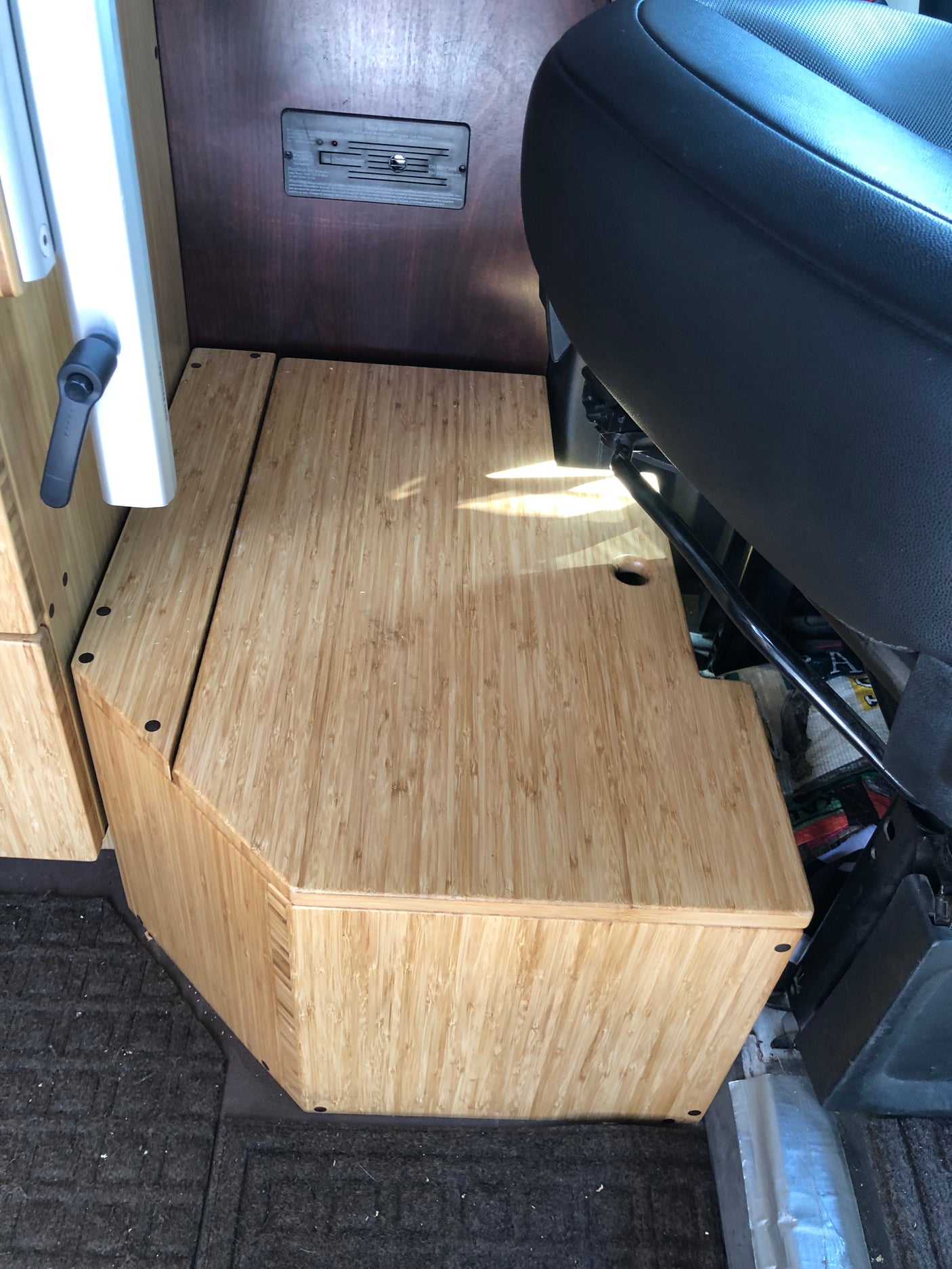 RV rental: custom bamboo storage unit, passenger seat, and wall-mounted control panel in a camper van.