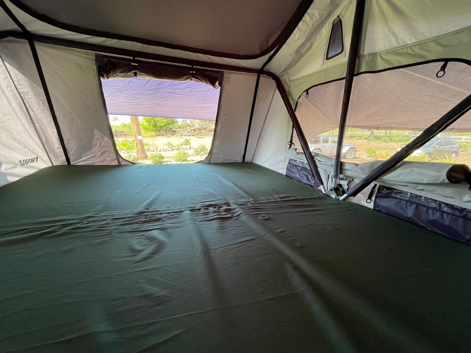 Spacious rooftop tent interior, ready for your next rv rental adventure. Features comfy bed, open windows, & outdoor views.