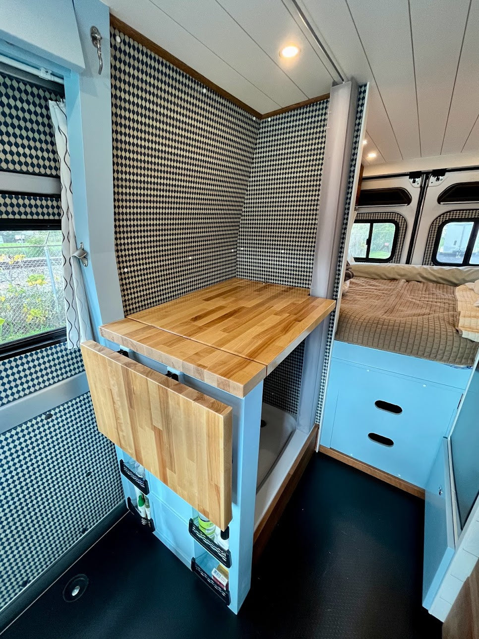 RV rental: Stylish camper van interior with compact kitchen, folding table, hidden shower, and comfy bed for mobile living.