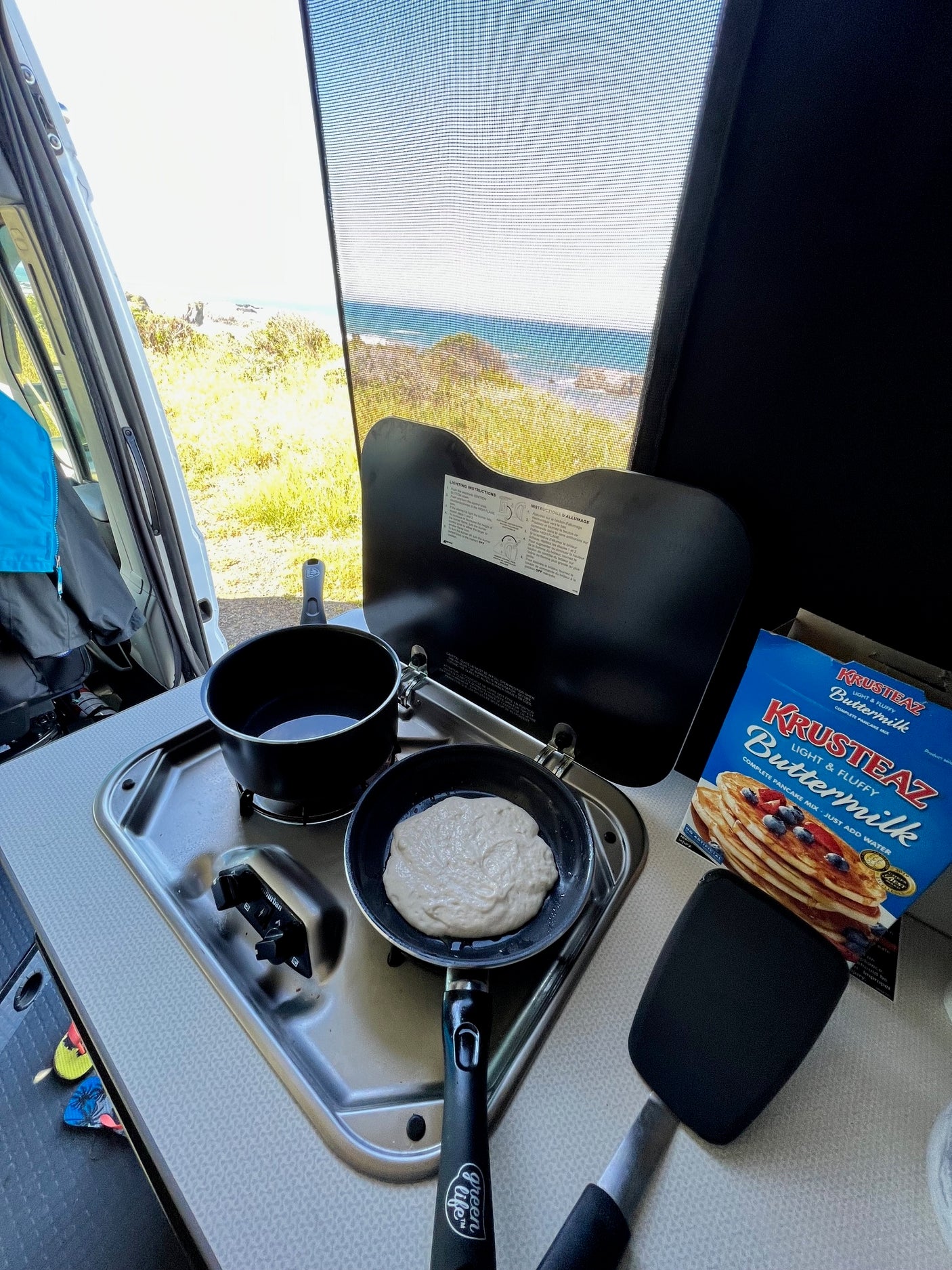 RV rental breakfast: Pancakes cooking on the stovetop with a beautiful ocean view.