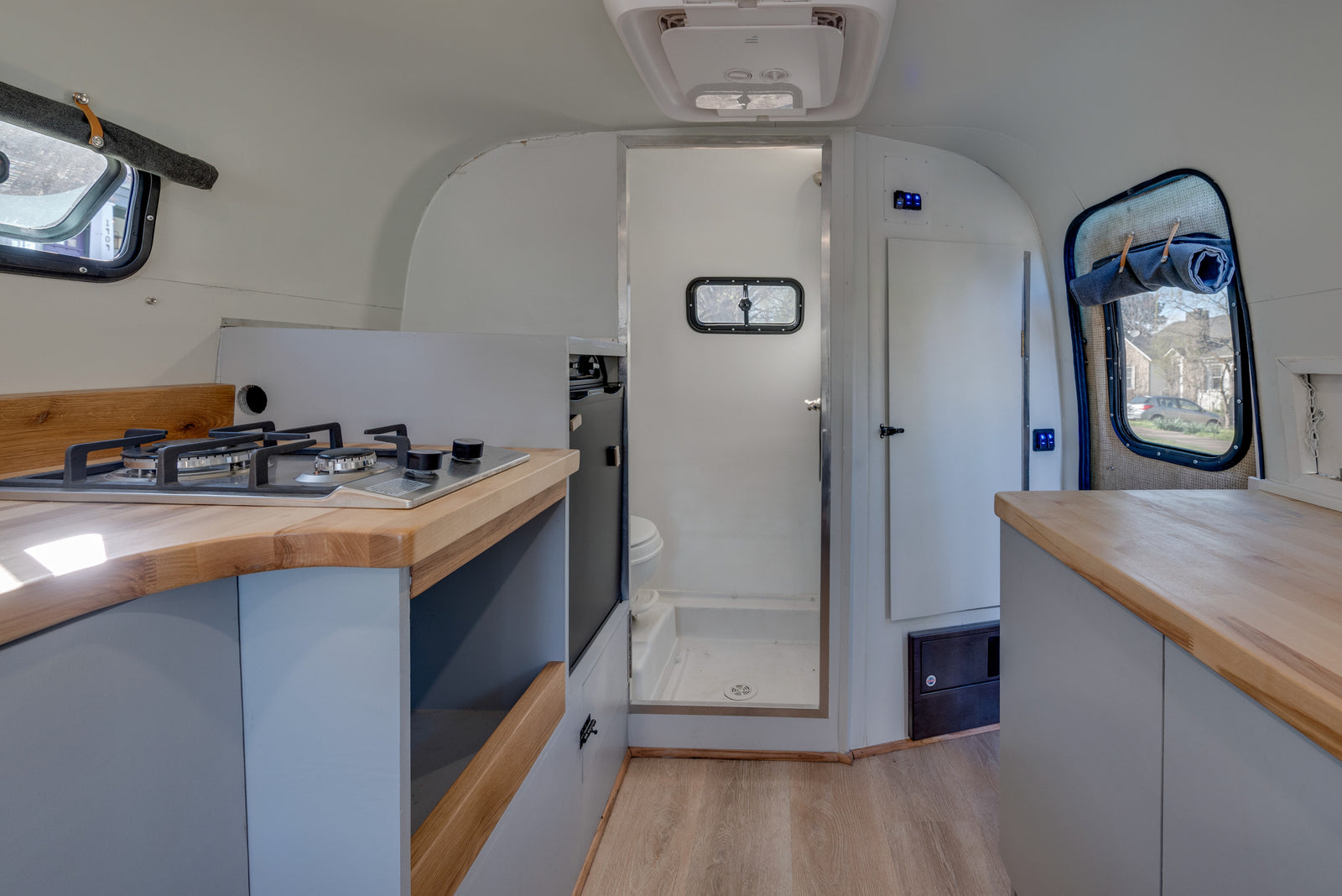 Explore this RV rental's interior: a compact kitchenette, a shower, and bright windows define this cozy camper.