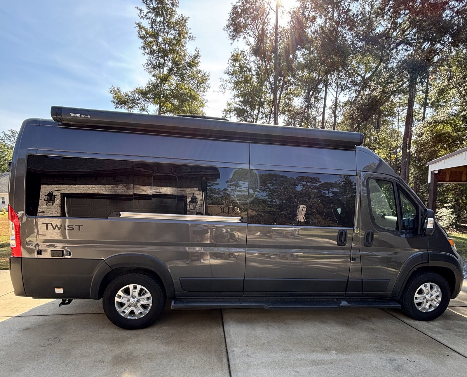 Dark gray camper van with a Thule awning, ideal for RV rental adventures. "TWIST" branded on the rear.