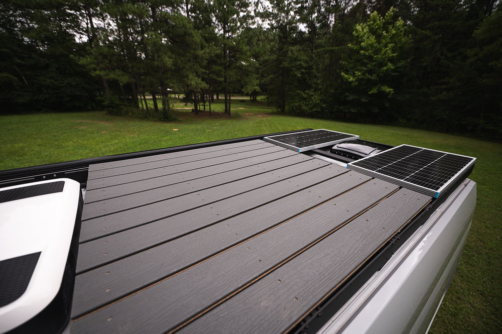 RV rental featuring roof solar panels and spacious deck for off-grid camping and outdoor living.