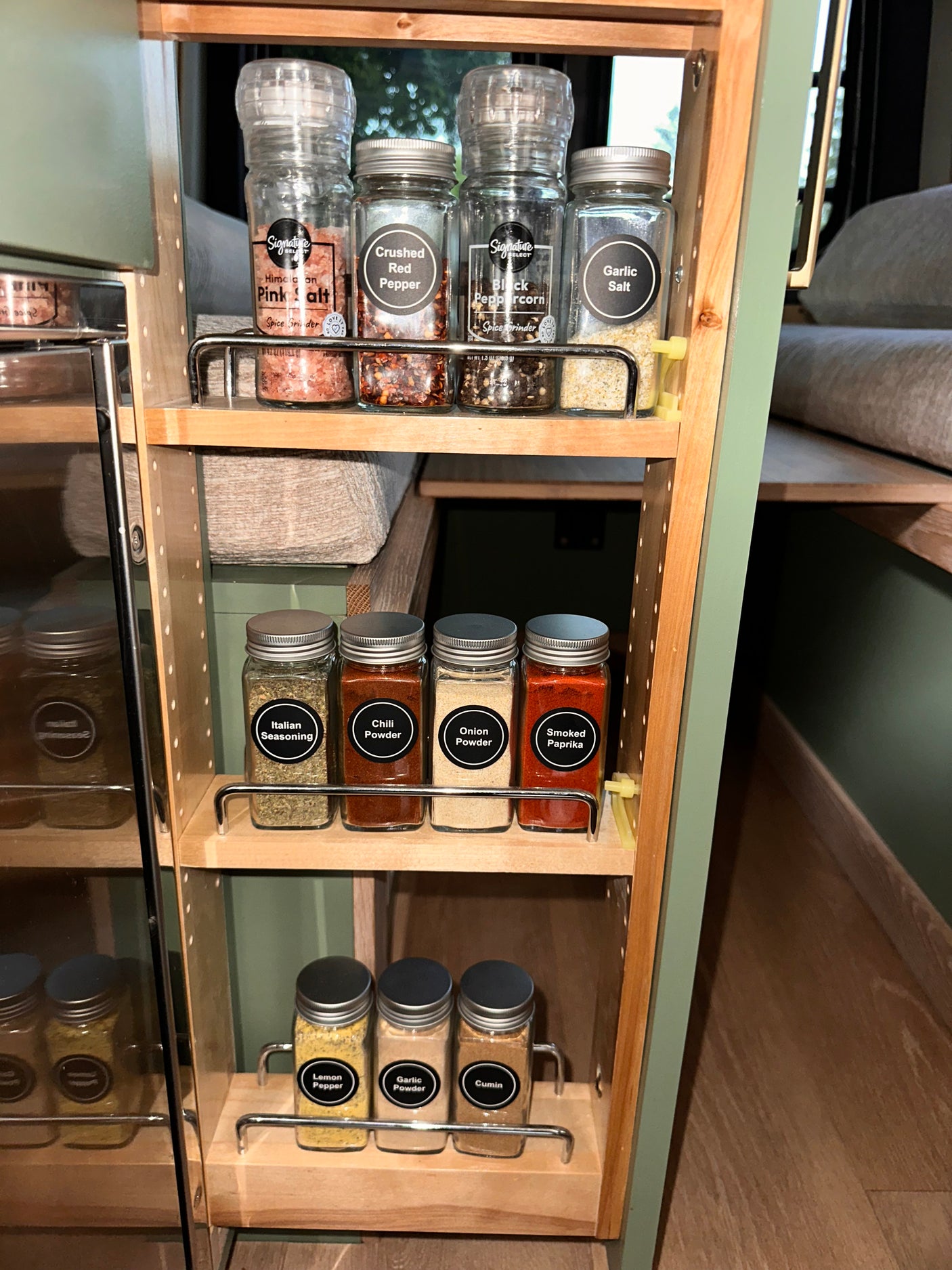 Convenient spice storage in an RV rental, featuring labeled jars of salt, pepper, chili, and more for easy cooking.