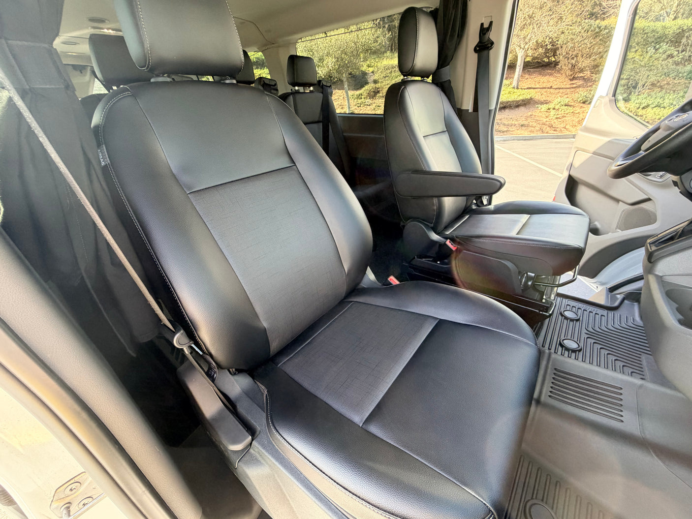 Spacious RV rental front cabin with black seats, white stitching, and custom floor mats, offering comfort for journeys.