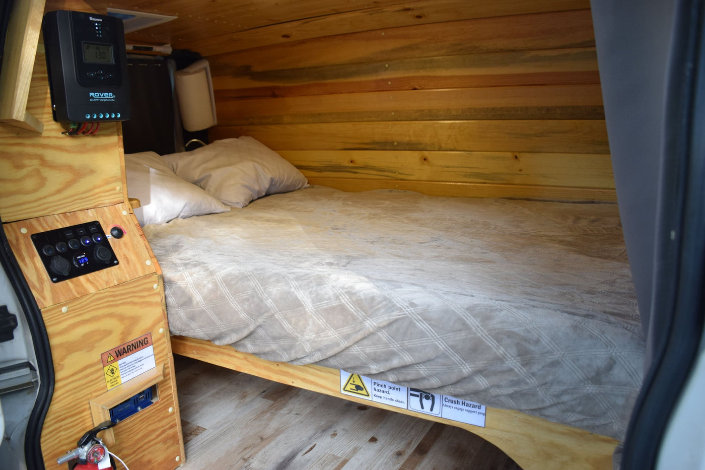 and electrical panel featuring 12.9V display.|Cozy wood-paneled RV rental interior with a green bench bed — photo 8