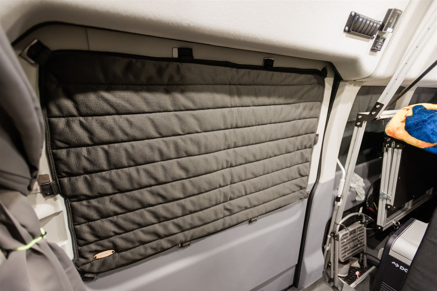 Dark grey quilted window insulation ensures comfort and privacy inside this RV rental, showcasing practical van features.