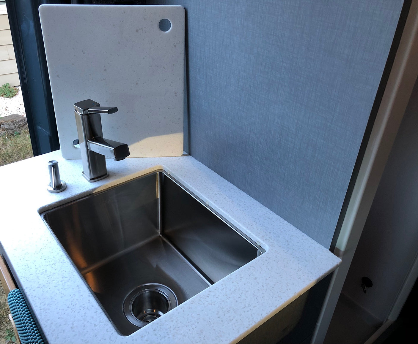 Modern kitchen in an RV rental with a stainless steel sink, sleek faucet, and white speckled countertop. Compact and functional.