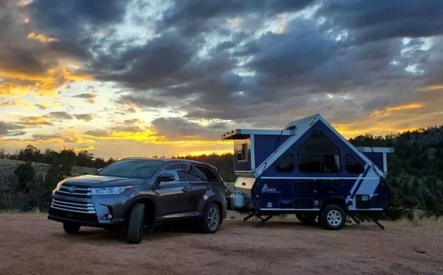 Beautiful sunset view with an SUV and A-frame pop-up camper, ideal for your next RV rental adventure.