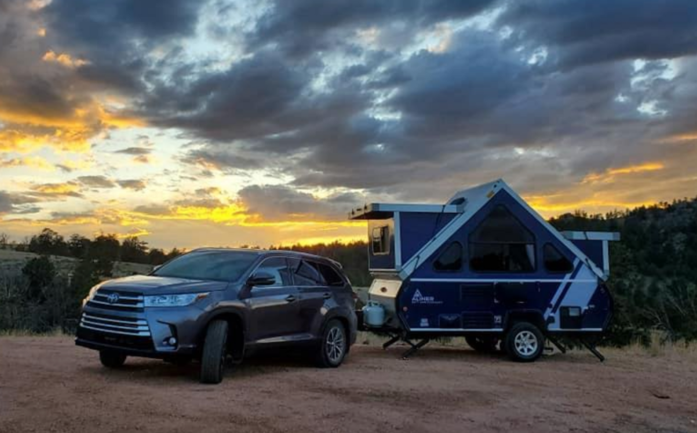 Beautiful sunset view with an SUV and A-frame pop-up camper, ideal for your next RV rental adventure.