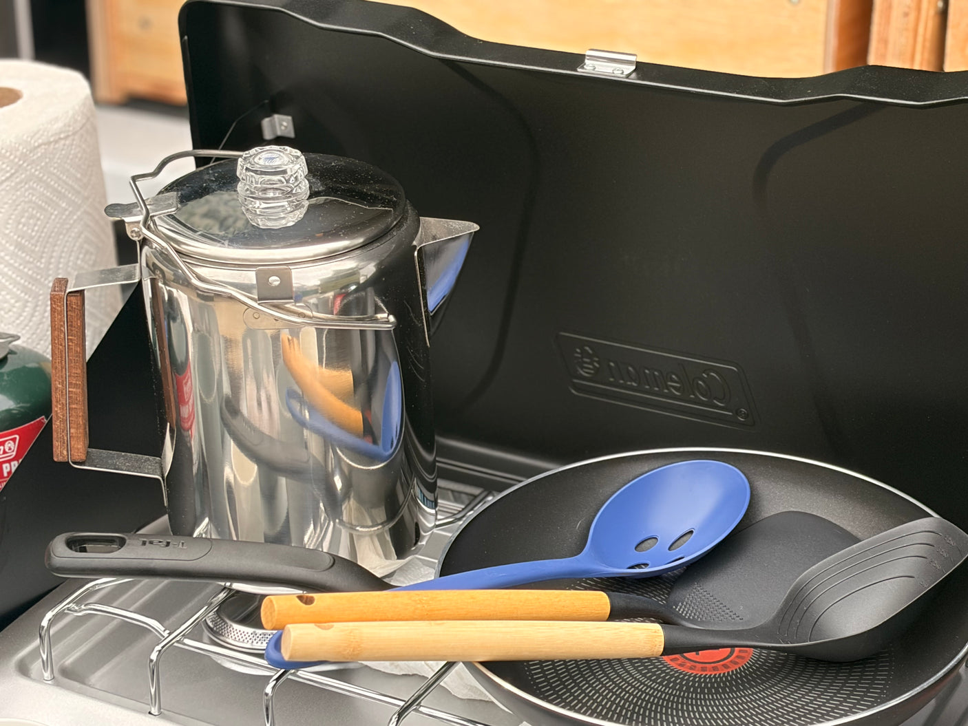 RV rental cooking essentials: a percolator coffee pot, Coleman camping stove, frying pan, and utensils for your outdoor meals.