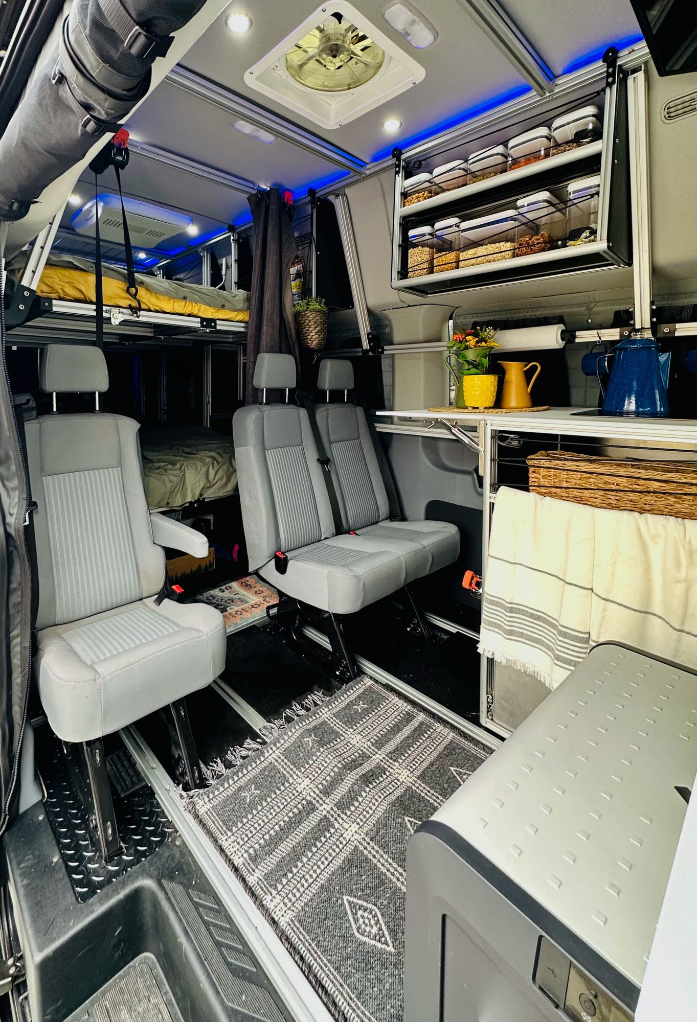 featuring comfy pillows & a stylish rug.|Inside a compact RV rental