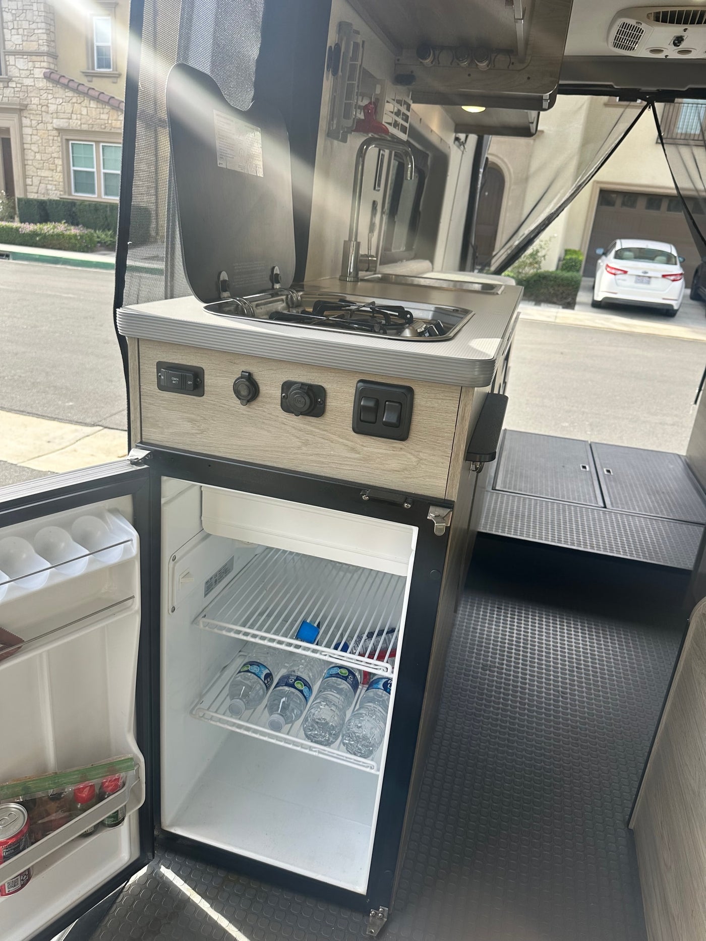 and sunny landscaping outside.|View of an RV rental camper van's interior: front seats — photo 4