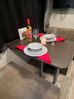 Cozy RV rental dining setup with wine and place settings for two, perfect for a romantic getaway.