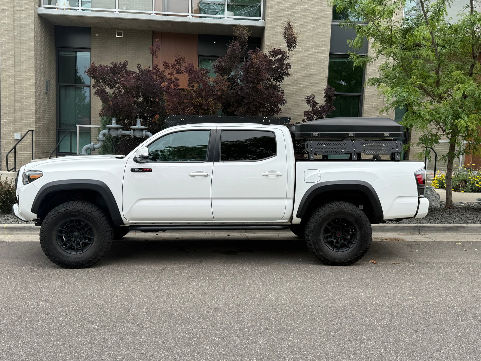 A white Toyota Tacoma TRD Pro pickup truck with a rooftop tent, an overlanding rig ready for adventure, like an RV rental.