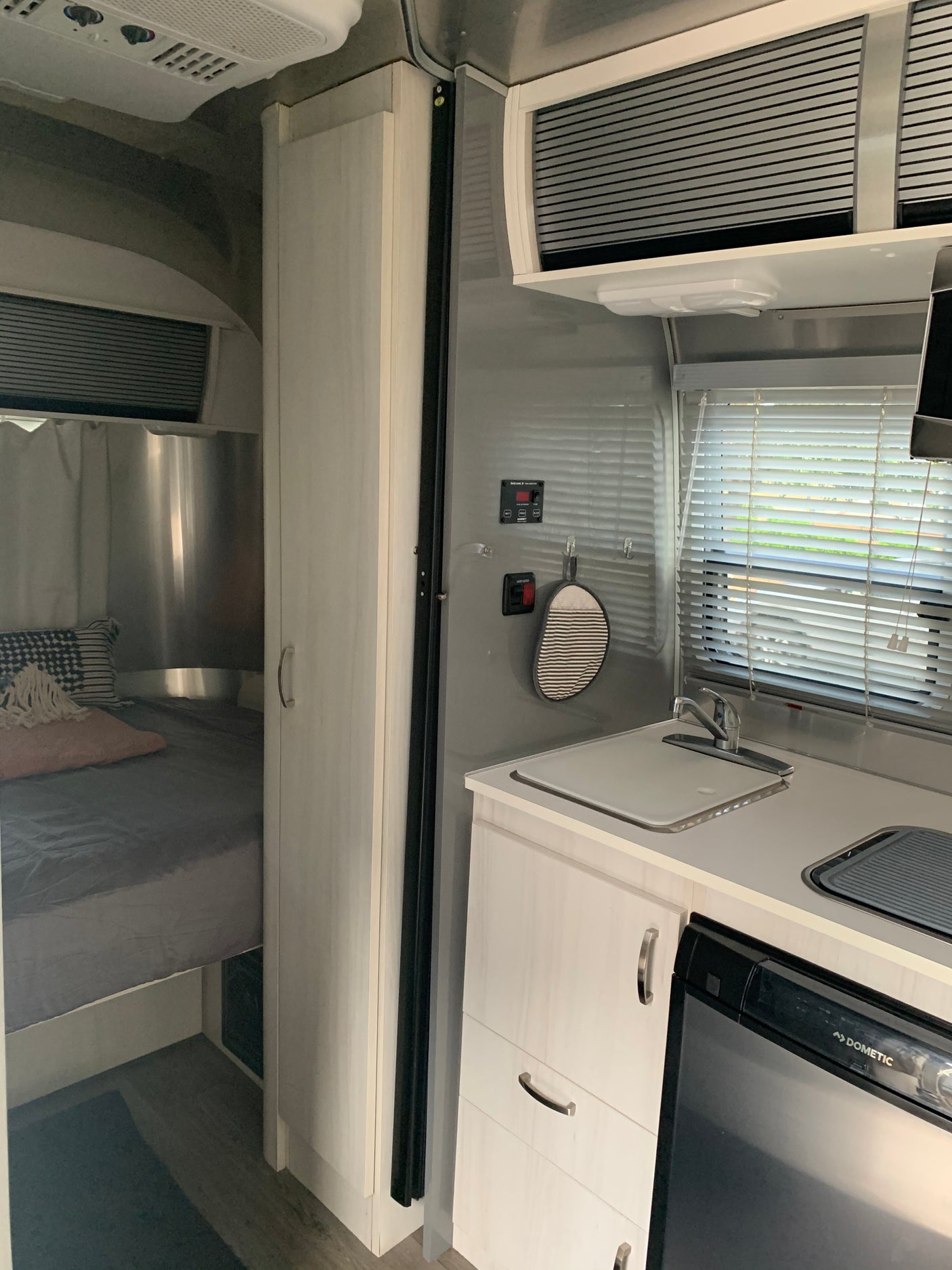 RV rental: Modern interior shows a bright kitchen with sink, compact fridge, and a cozy bed area with light wood finishes.