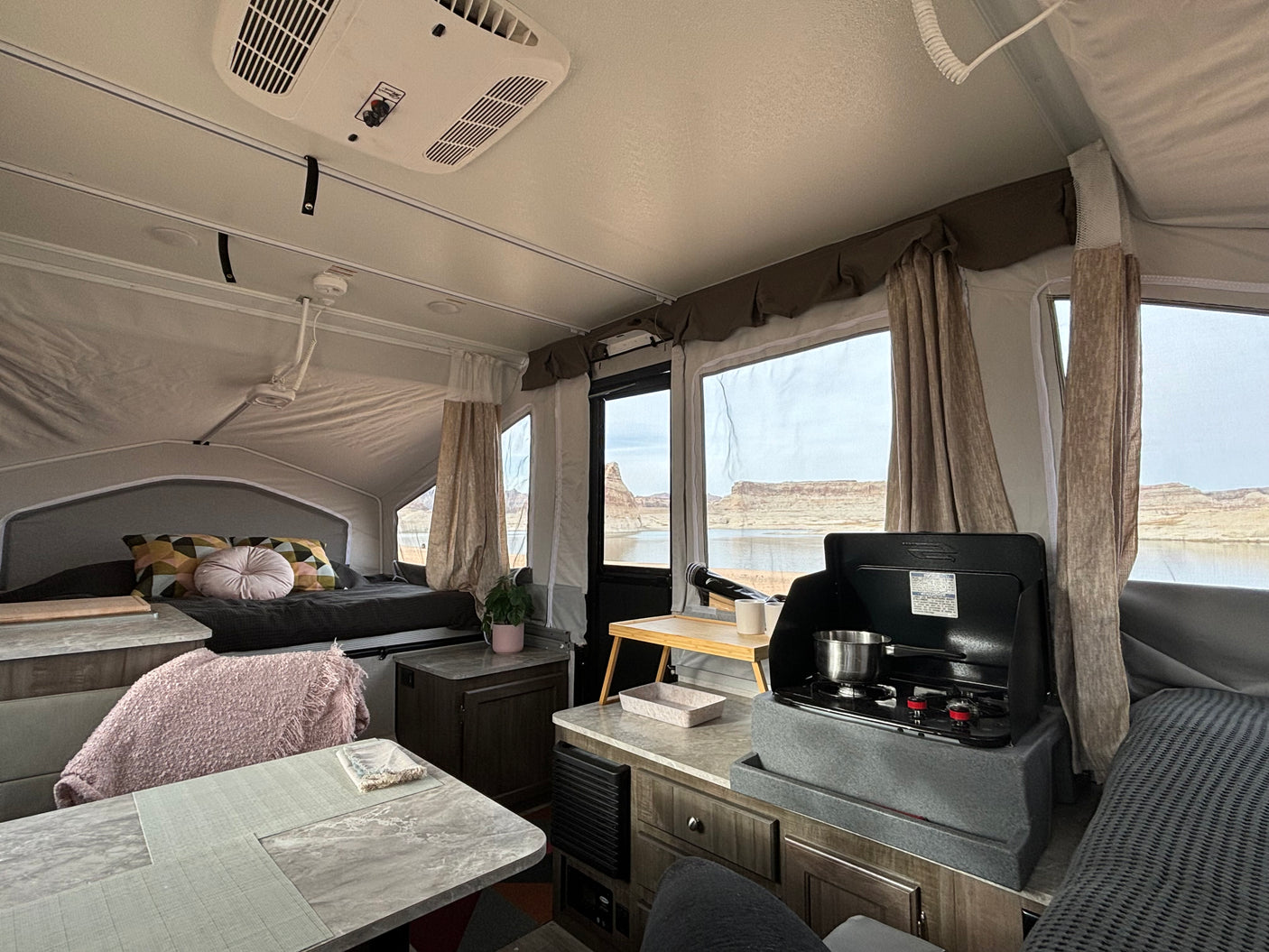 Cozy RV rental pop-up camper interior with a bed, compact kitchen, and scenic lake views for your next adventure.