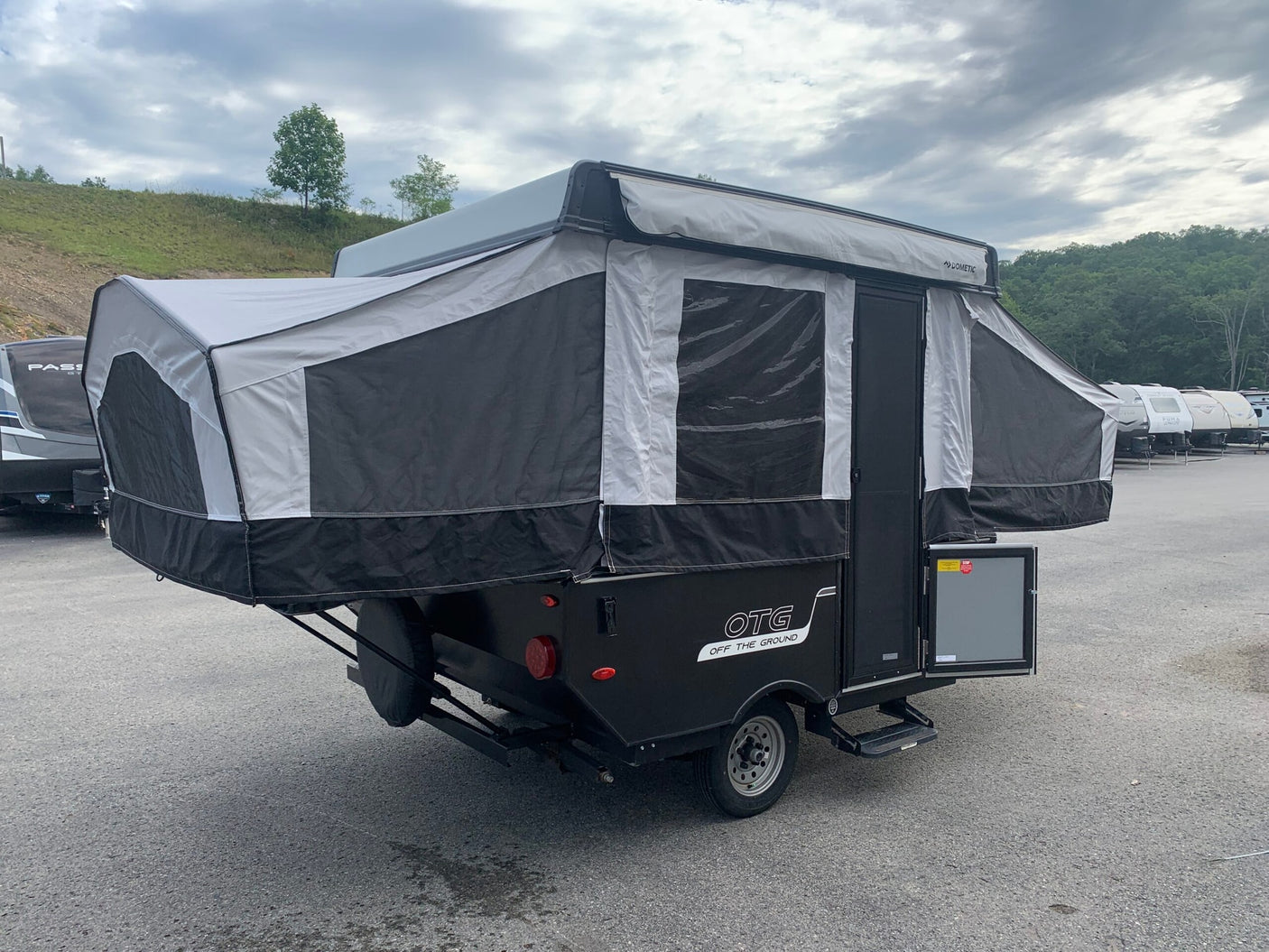 This black and white OTG pop-up camper is ready for RV rental, fully set up with extended fabric sides and Dometic awning.