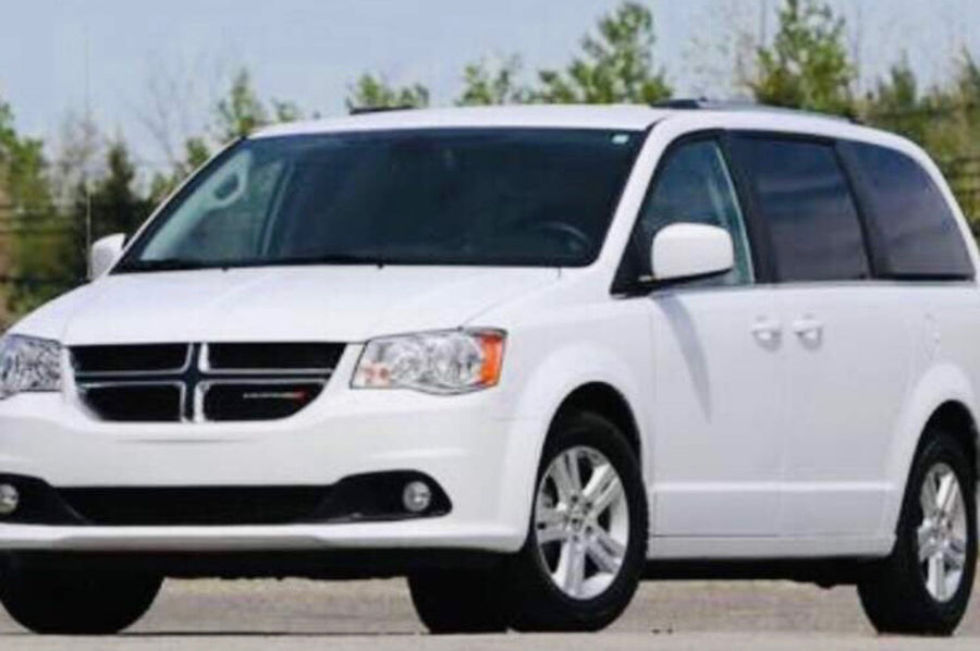 A white Dodge Grand Caravan minivan shown, suitable for family road trips. Explore this option for your next adventure or RV rental needs.