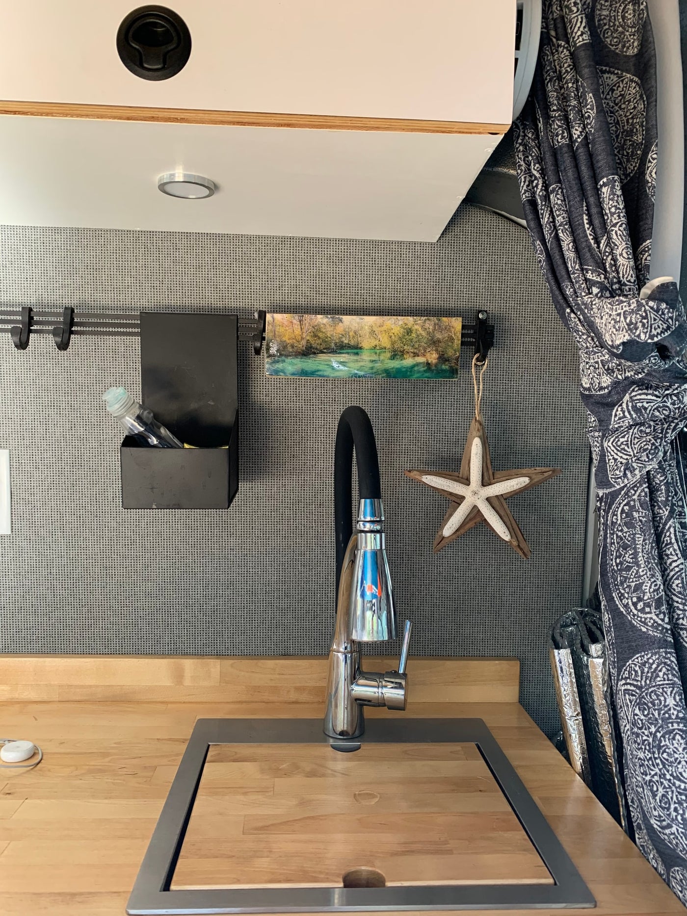 This RV rental offers a well-designed kitchen, with a chrome faucet, wooden counter, and organized wall storage options. — photo 4