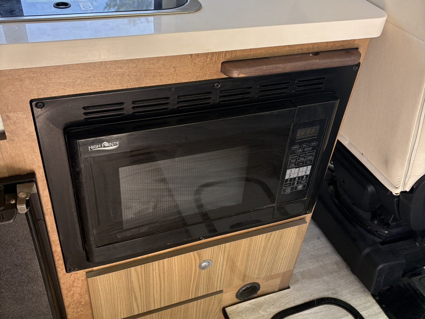 This RV rental features a built-in HIGH POINTE microwave, seamlessly integrated into the wood cabinetry for convenient cooking on the go.