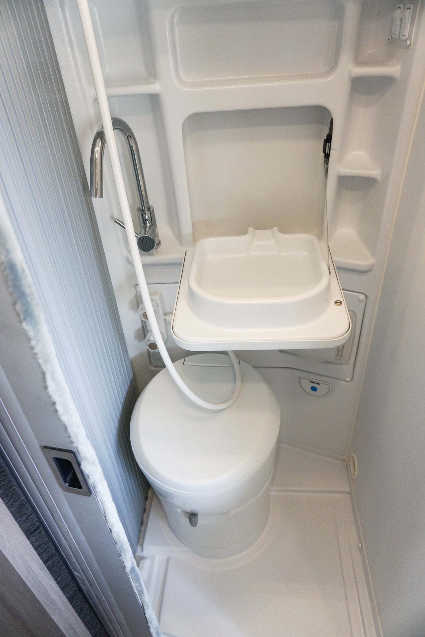 Inside a compact **rv rental** bathroom, featuring a fold-down sink, toilet, and integrated shower for efficiency.