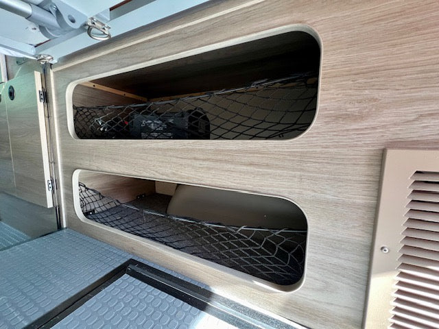 RV rental storage: Two built-in compartments with mesh netting securely hold items, perfect for camper van organization.