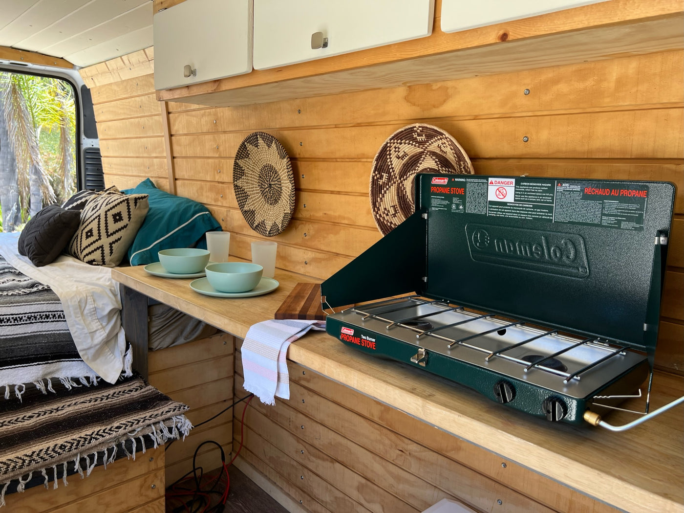 Inside a functional rv rental camper van, featuring a bed, kitchen counter, and portable propane stove for trips. — photo 7