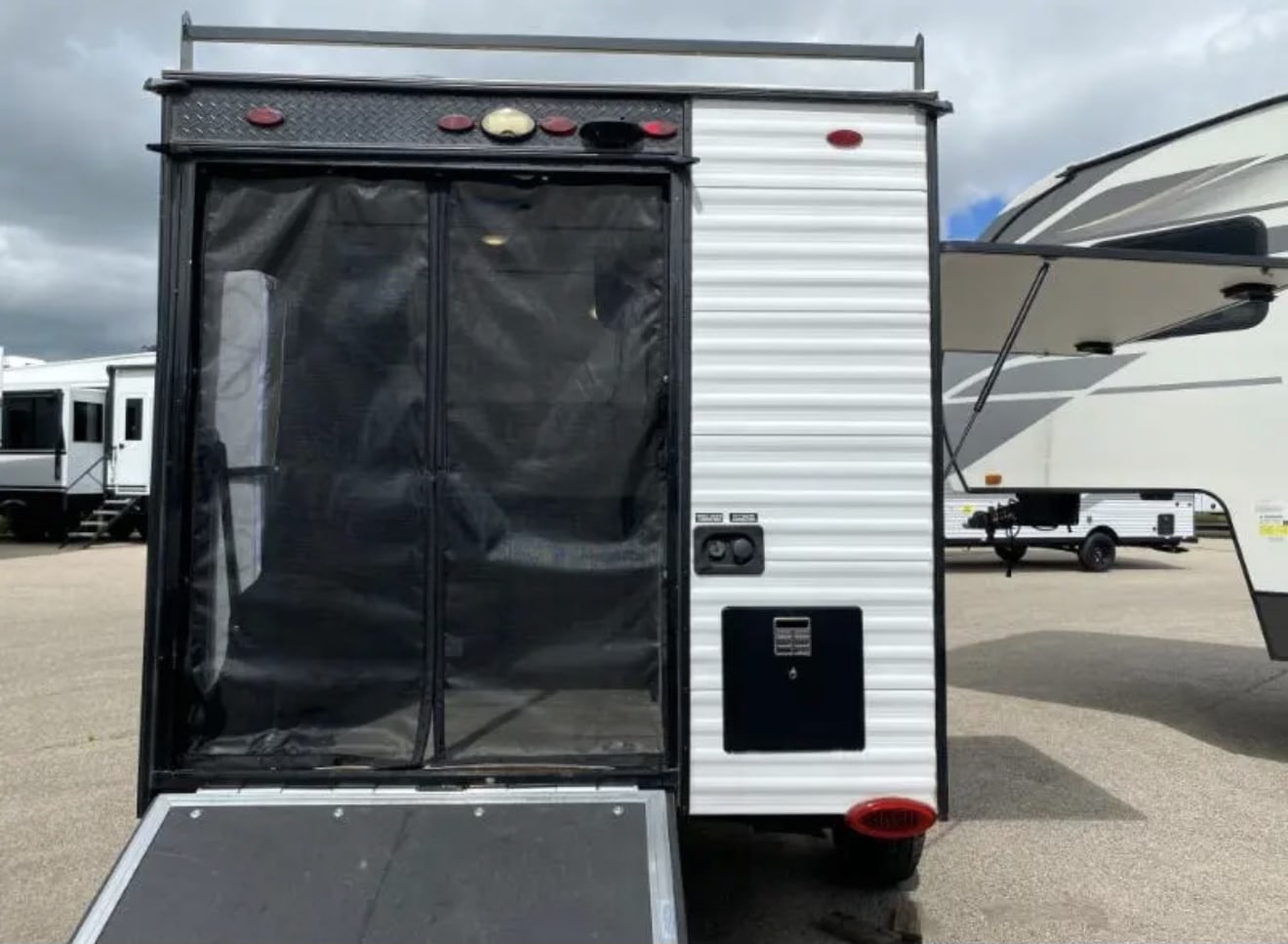 next to a seating area.|RV rental: Interior of a toy hauler camper with a folded bed
