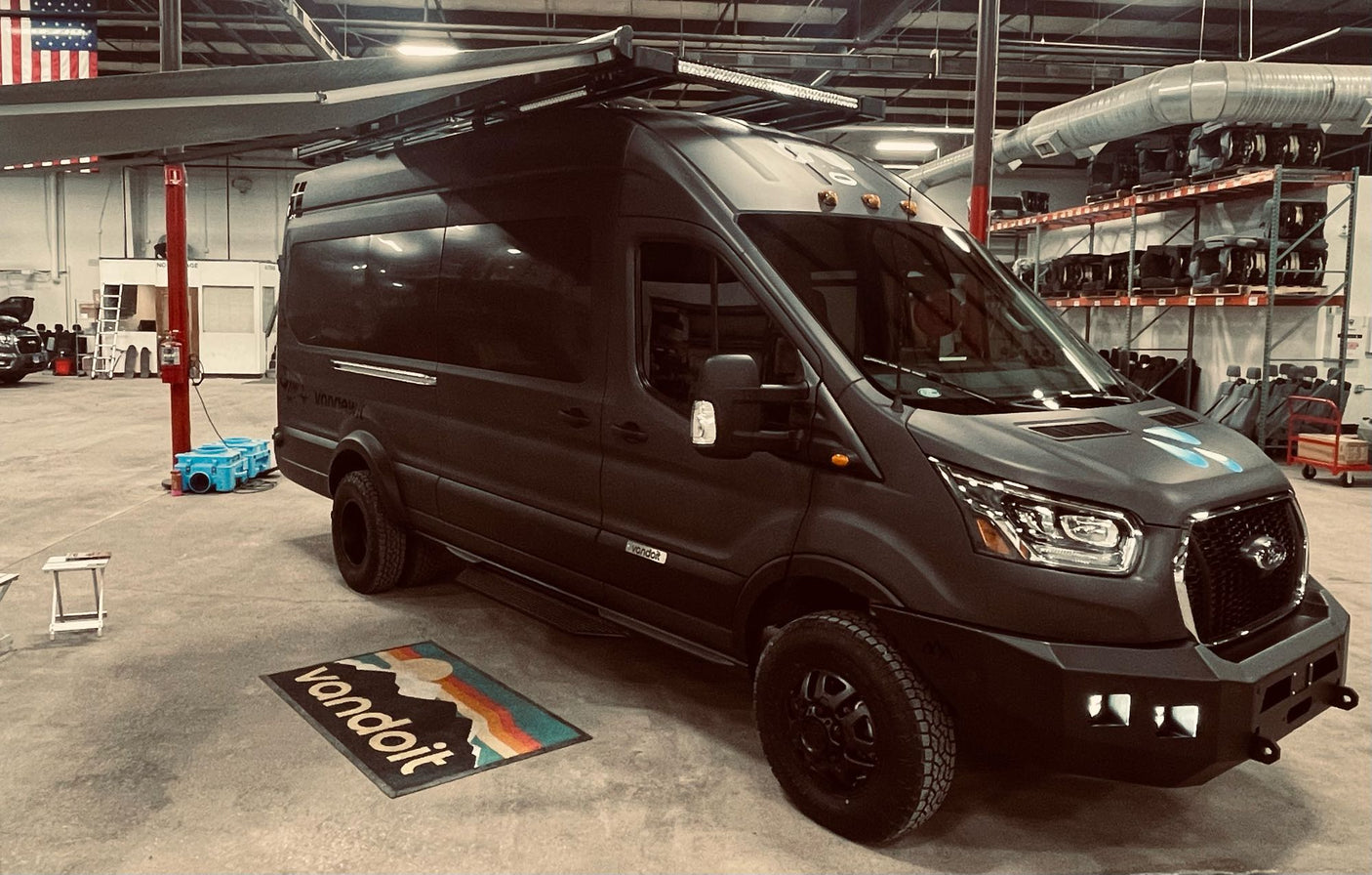 A custom dark grey Vandoit Ford Transit adventure van with off-road tires & roof rack