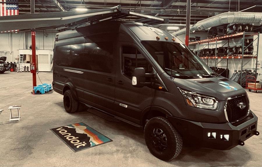 A custom dark grey Vandoit Ford Transit adventure van with off-road tires & roof rack