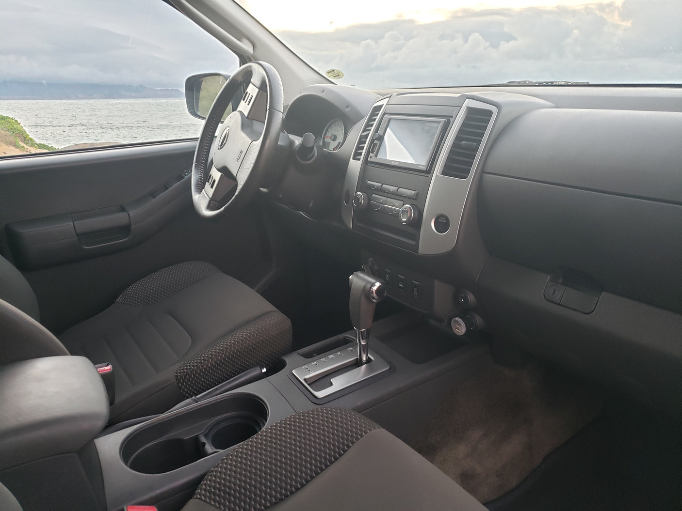 View from a spacious SUV interior, dashboard & seats visible, with a stunning ocean vista. Ideal for your next travel or **rv rental** adventure!