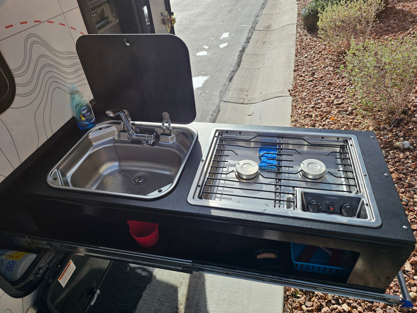 RV rental outdoor kitchen with a Dometic stove, sink, and Dawn dish soap, ready for cooking and cleanup on the go.