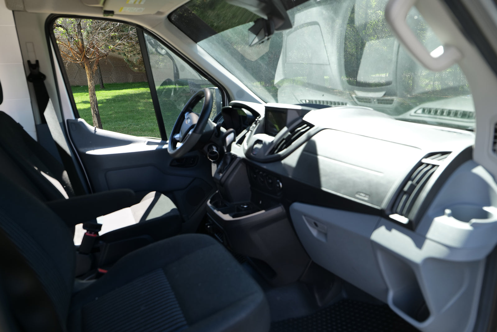 Spacious RV rental van interior, featuring the driver's cabin, dashboard, steering wheel, and front seats.