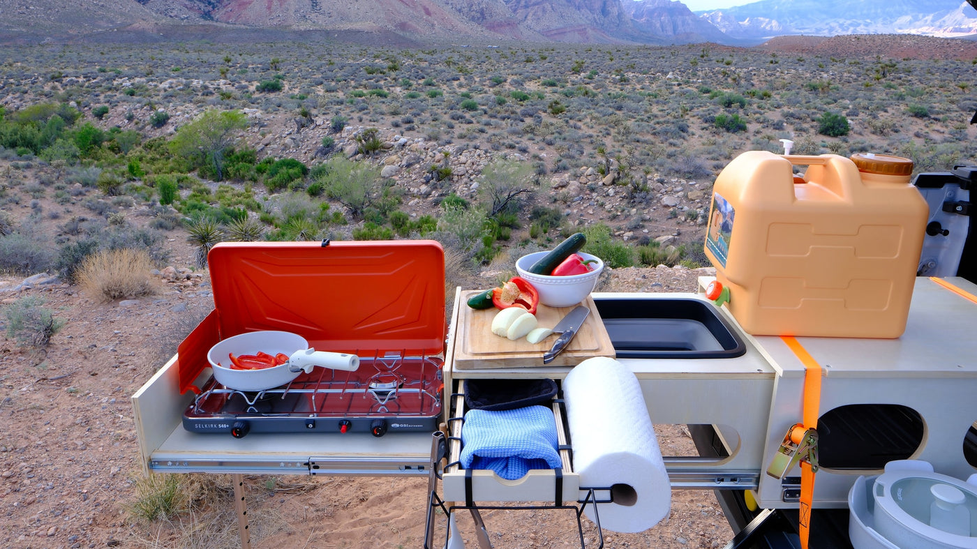 Cooking outdoors from an RV rental: portable kitchen with stove, fresh vegetables, water, set against a vast desert & mountains. — photo 16