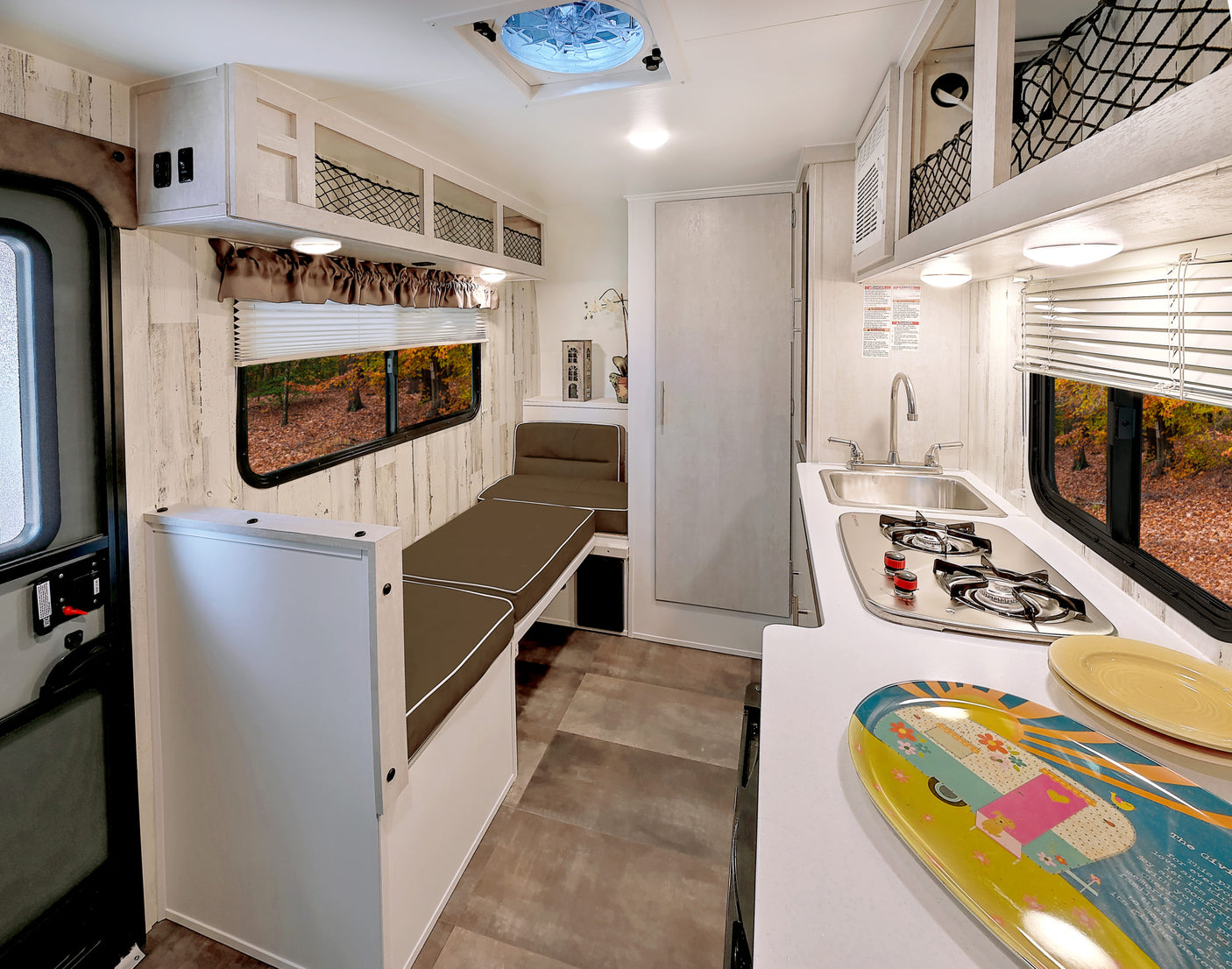 This RV rental interior features a compact kitchen, comfy seating that converts to a bed, and overhead storage.