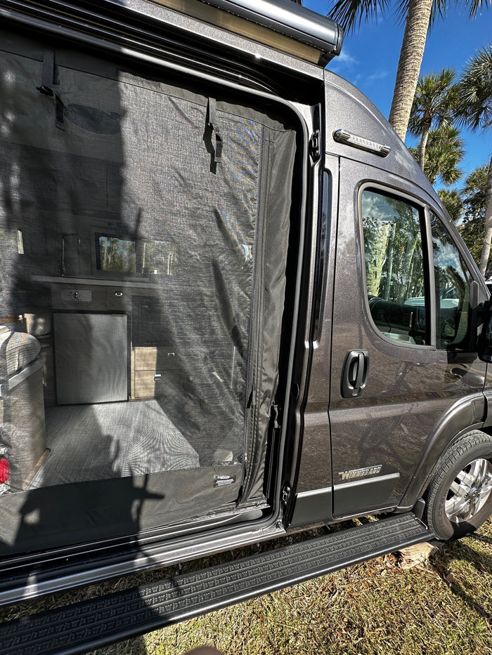 This grey Winnebago RV rental has its side door open, showcasing a mesh screen and interior details, with palm trees visible.