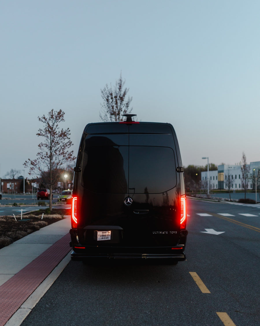 Black Mercedes-Benz Sprinter van, ideal for rv rental, seen from the rear at dusk with glowing red taillights and an Ohio plate.