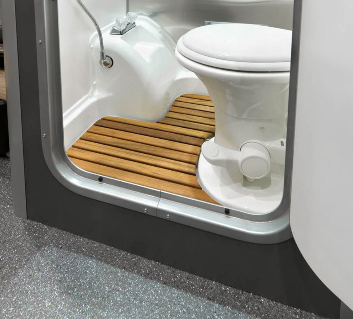Compact **RV rental** wet bath: white toilet, shower, and wooden slatted floor optimize small spaces. Ideal for campervans.