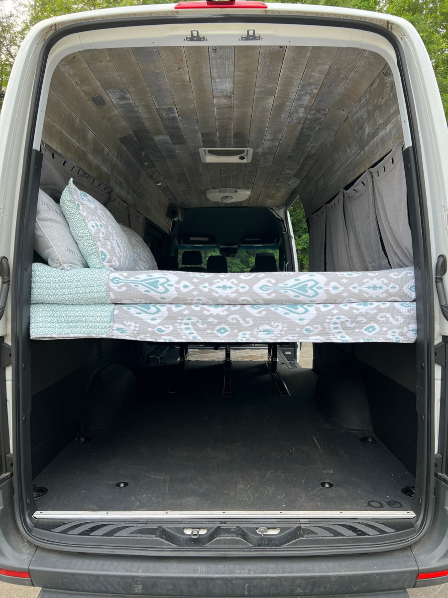 Spacious camper van conversion for your next rv rental adventure. Features elevated bed, wood ceiling, and ample storage.