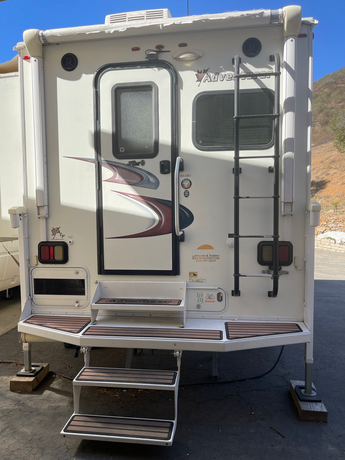 Rear view of an Adventurer truck camper RV rental with extended steps, ladder, and awning. Ready for adventure! — photo 3