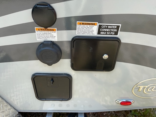 Crucial RV rental hookups: 30A power and city water (max 50 PSI) connections, plus lower service access points.