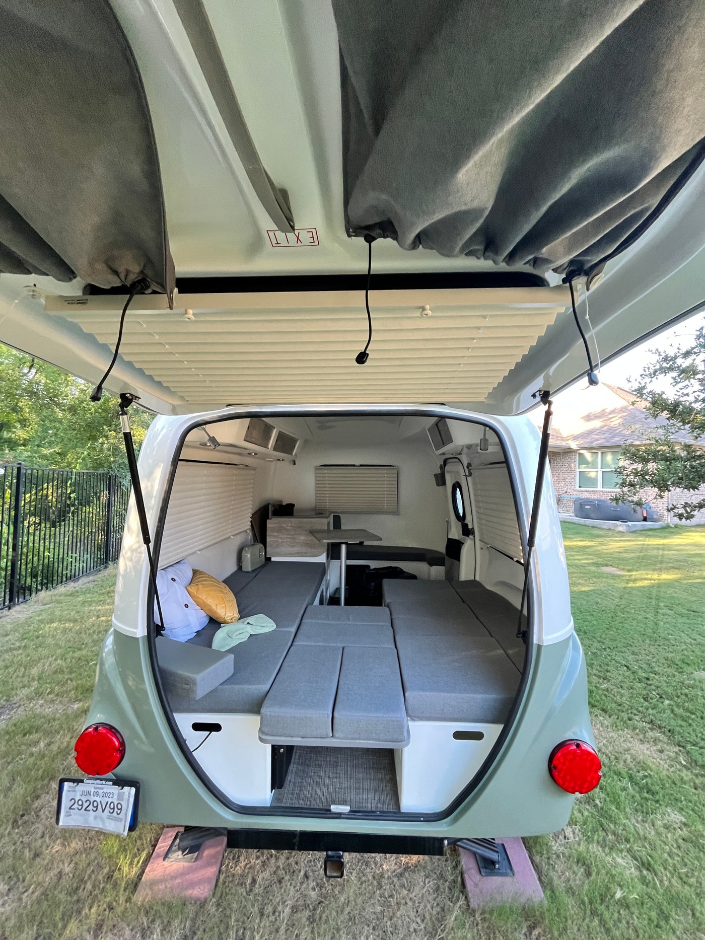 Inside a cozy RV rental: The rear of a compact camper showing its convertible bed layout and open hatch. — photo 9